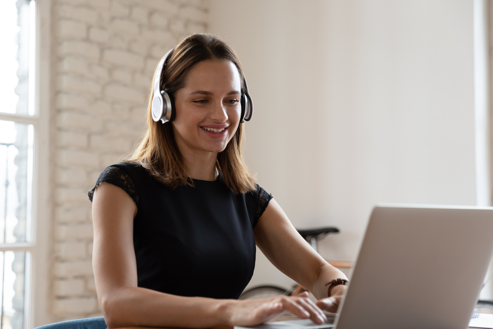 Smiling woman wearing wireless headphones working
