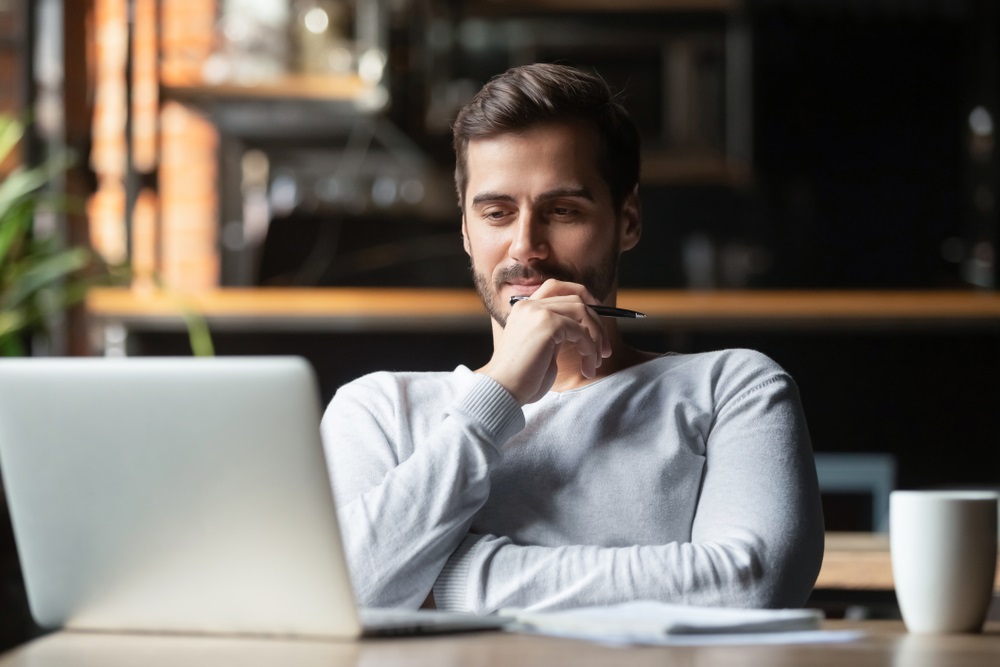 man thinking of online job search looking at laptop