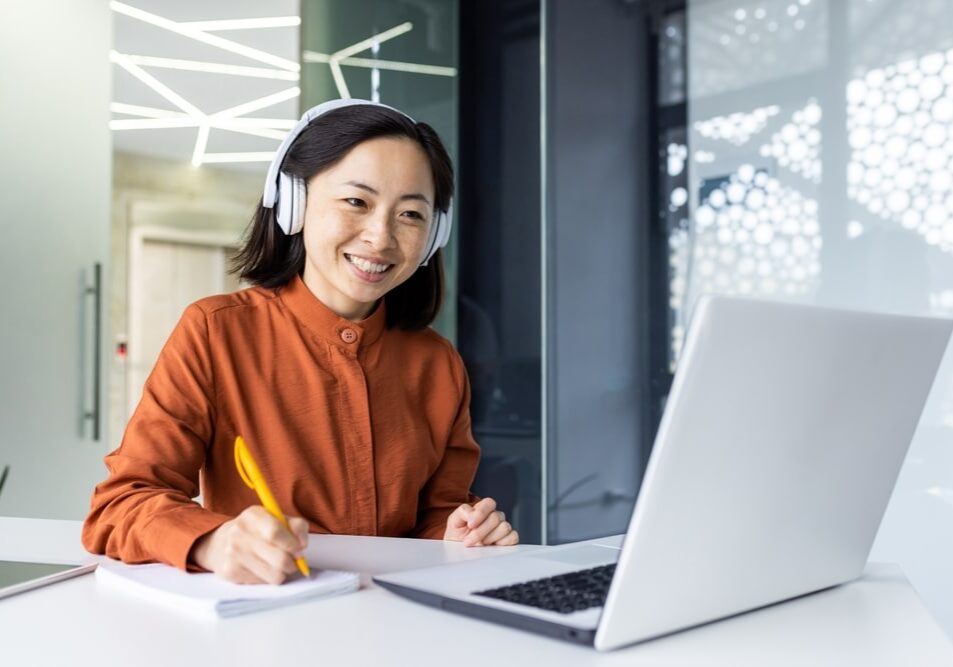 Asian business woman with headphones watching online training course